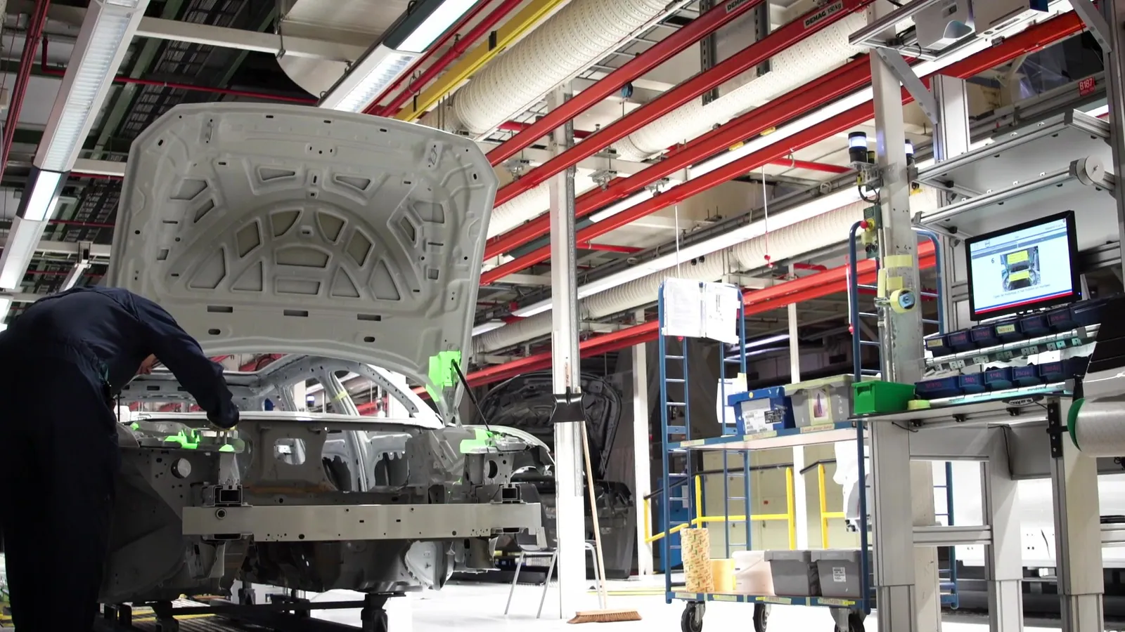 Operator placing components on a car body while projected guidance highlights the target positions